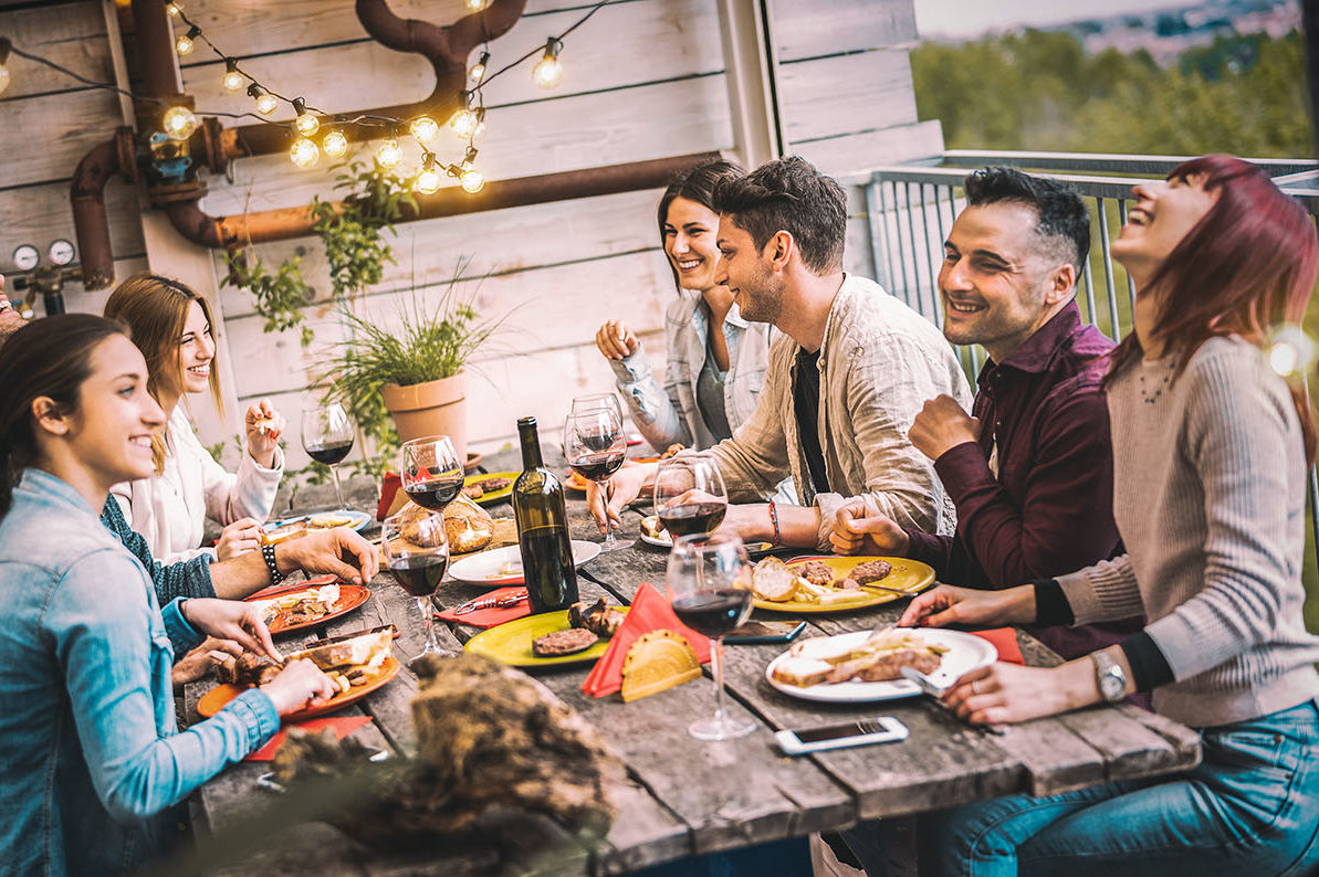 Young people dining and having fun drinking red wine together on